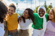 © Xavier Lorenzo - Multiracial female friends laughing and walking outdoors. Diverse young women enjoying a sunny day and celebrating friendship. Community and happiness concept.