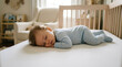 © Muhammad - A baby sleeps peacefully on a mattress in a nursery with furniture.