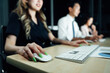 © AU USAnakul - People Collaborating on a Project: An Asian professional uses a mouse on a wooden desk in a modern office, working with a keyboard and computer monitor, focused on a design concept.