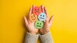 © UmerDraz - Hands hold colorful speech bubbles depicting different emotional expressions on a vibrant yellow background