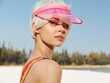 © SHOTPRIME STUDIO - Portrait of a stylish woman on a sunny beach wearing a pink visor, sunlit skin, and soft makeup, capturing a carefree summer vibe and bold accessory.
