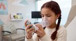 © Mirala - Young girl using an asthma inhaler with a spacer and face mask in a pediatric clinic, respiratory health, child medical care, asthma treatment.