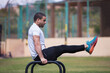 © .shock - Man doing L-sit calisthenics on parallel bars during outdoor crossfit fitness workout with a friend