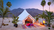 © Kashif - A luxurious desert glamping setup with a white tent and palm trees at dusk