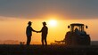 © tashechka - Farmers shake hands during sunset with tractor in background on a field