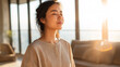 © AS_SleepingPanda - A young woman meditates peacefully by the window as the warm sun illuminates her face