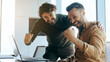 © Prostock-studio - Two men show excitement while looking at a laptop screen in a bright office. They are smiling and sharing a moment of joy as they celebrate something important together.