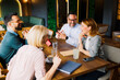 © djile - Four friends or colleagues are laughing and talking together at a table in a modern cafe