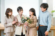 © buritora - A smiling businesswoman receives a bouquet of flowers, while her team members applaud.