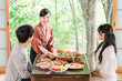 © buritora - A female inn staff member/maid explains the meal in a guest room at a hot spring inn.