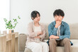 © buritora - A young Asian couple sitting on the living room sofa discussing their problems.