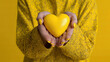 © Dilruba - Hands holding yellow heart on matching background representing mental health and awareness message