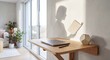 © Nguyen Tuan - Minimalist workspace with a laptop and a creative shadow of a woman holding a book cast on the white wall, conceptual education and work theme