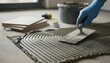 © Bellal - Hand of a construction worker in blue glove applying adhesive for floor tiles