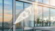 © CK Studio - Professional power washing of dirty glass windows on a modern office building, reflecting sunlight and sky, symbolizing commercial cleaning and maintenance.