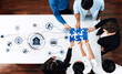 © InfiniteFlow - A diverse group of professionals collaborate at a modern conference table, assembling a puzzle piece while surrounded by digital icons representing innovation and teamwork concepts. Trope
