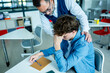 © Halfpoint - Teacher supporting struggling student with learning difficulties during lesson.