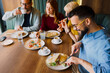 © djile - Group of friends having lunch together in cafe and enjoying food