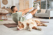© Pixel-Shot - Sporty young man with Australian Shepherd dog training on mat at home