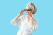 © Pixel-Shot - Pretty young woman after shower wearing sunglasses on blue background