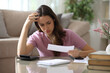 © PheelingsMedia - Worried woman checking invoice and accounting at home