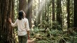 © Николай Срибяник - Senior woman touching redwood tree looking up at sunbeams in peaceful forest