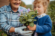 © Halfpoint - Elderly woman and little granddaughter planting flowers together in spring garden.