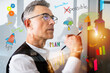 © alphaspirit - Business professional writing on glass with colorful drawings in a meeting room in the afternoon