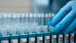 © wedmoments.stock - Laboratory technician wearing blue gloves handling test tubes in a laboratory setting, with organized racks and clear labels visible in the background