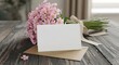 © MindRender - Blank greeting card on a brown envelope with a bouquet of pink flowers on a rustic wooden table