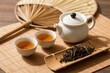 © zhang yongxin - Traditional tea set with teapot, cups, dried tea leaves, and bamboo fan on a wooden mat