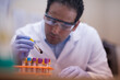 © .shock - Lab technician carefully handling blood test sample in clinical laboratory wearing gloves and goggles