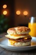 © Maryna - Savory breakfast sandwich on a biscuit. Egg, sausage, and melted cheese layered between a soft bun. Served with orange juice and soft bokeh lights background.