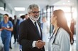 © Prazis Images - Hospital Administrator Shaking Hands with a Female Doctor in a Busy Hallway