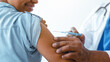 © Prostock-studio - A person is getting a vaccine in a clinic. A healthcare worker is giving the injection into the person's arm. The setting appears clean and professional.