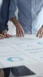 © rogerphoto - Business colleagues are examining financial data, pointing at charts and graphs spread out on a table during a collaborative analysis session in a modern office.