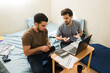 © AntonioDiaz - Latin men budgeting and calculating finances, managing household bills while counting money in their first apartment