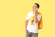 © Pixel-Shot - Handsome young happy man with headphones talking by mobile phone on yellow background