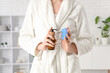 © Pixel-Shot - Young woman with hair scalp massager and bottle of cosmetic product after shower at home, closeup