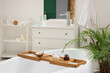 © Pixel-Shot - Wooden tray with coconut and cosmetic products on white bathtub in modern bathroom
