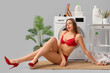 © Pixel-Shot - Attractive young woman in underwear doing laundry on light background