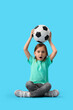 © Pixel-Shot - Shocked little girl with soccer ball sitting on blue background