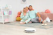 © Pixel-Shot - Happy family with robot vacuum cleaner hugging in children's bedroom