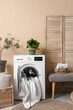 © Pixel-Shot - Laundry room interior with washing machine, grey bench and houseplants