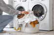 © Pixel-Shot - Young woman putting dirty clothes into washing machine in laundry room, closeup