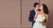 © Pixel-Shot - Young wedding couple kissing near brown wall. Banner for design