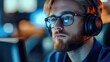 © Monika - focused young man wearing glasses and over-ear headset with microphone at a dimly lit computer station, face partially obscured by a square blur, cool blue and warm ambient lighting, concentrated