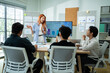 © Yingyaipumi - Happy young Asian Gen Z business team meeting and collaborate in modern office. Creative woman with orange hair discussing project strategy with colleagues. Concept of startup and youth empowerment.