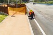 © Bohdan - Construction worker inspecting road surface with tablet near safety barrier
