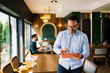 © djile - Young professional man using digital tablet while working remotely in modern cafe environment